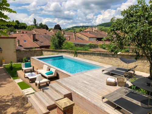 een zwembad in een tuin met een houten terras bij Maison TANDEM in Cluny