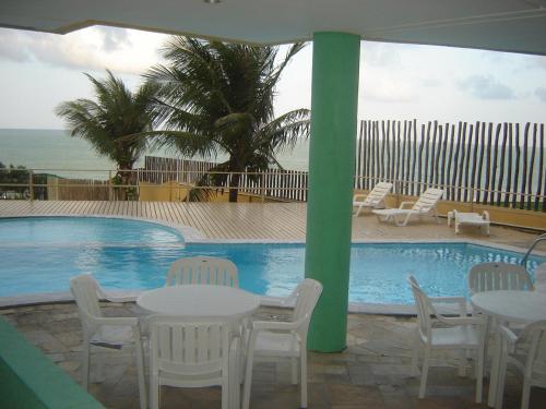 a swimming pool with tables and chairs next to a table and chairsktop at Atlántico Flat in Natal