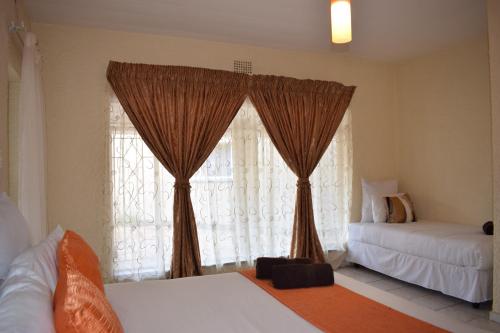 a bedroom with two beds and a window with curtains at Moye Guest House in Benoni