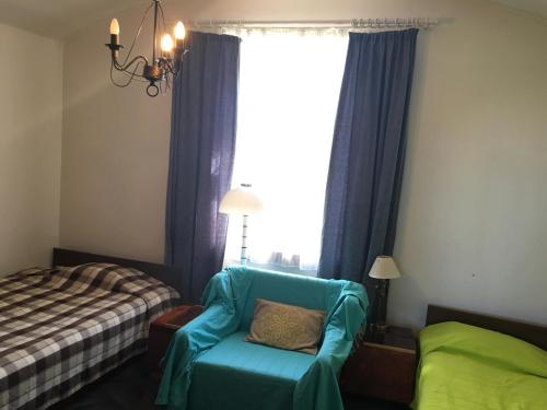 Un dormitorio con una silla azul, una cama y una ventana en Kähri Home Accomodation, en Valga