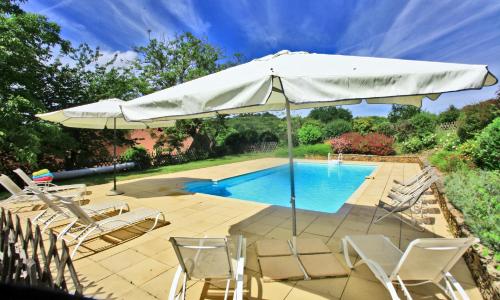 une terrasse avec des chaises et un parasol ainsi qu'une piscine dans l'établissement Gîtes de charme Le Cheyssignaguet, à La Chapelle-Aubareil