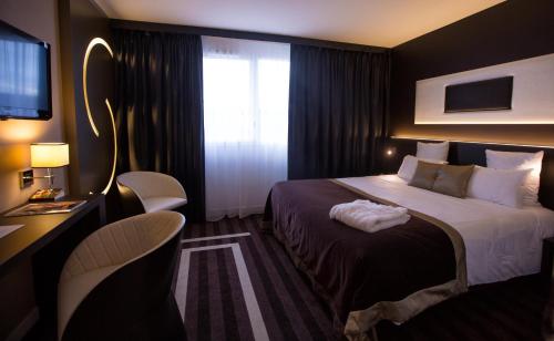 um quarto de hotel com uma cama e uma janela em LE COLISÉE Hotel & Spa NANTES Saint Herblain em Saint-Herblain