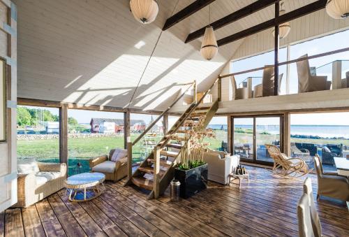 a living room with a staircase and a lot of windows at Bottengarn Boutique Guesthouse in Koguva