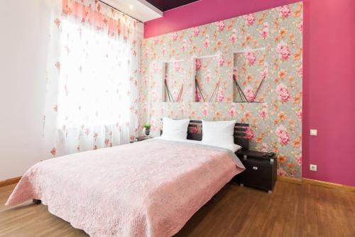 een slaapkamer met een groot bed met een roze muur bij Апартаменты двухкомнатные для 6х около парка в центре in Lviv