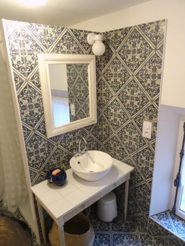 une salle de bain avec un lavabo et un miroir sur un mur dans l'établissement L'escalier des rêves gîte, à Saint-Sauveur-en-Puisaye