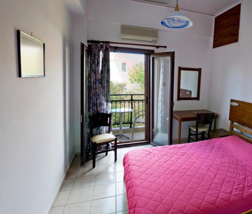 a bedroom with a pink bed and a balcony at Oasis Studios in Palaiochora