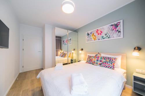 a bedroom with a large white bed and a mirror at GRANO APARTMENTS Gdańsk Motława SPA & Wellness in Gdańsk