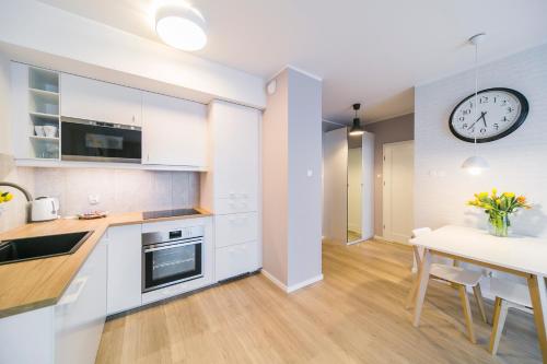 a kitchen with a table and a clock on the wall at GRANO APARTMENTS Gdańsk Motława SPA & Wellness in Gdańsk