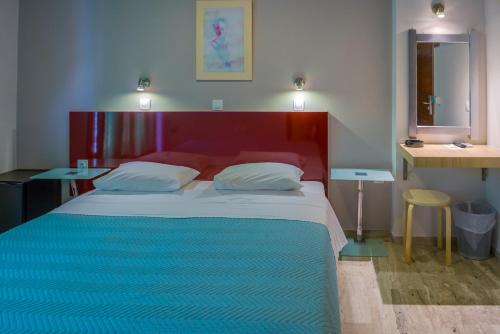 1 Schlafzimmer mit einem Bett mit einem roten Kopfteil und 2 Tischen in der Unterkunft Polyxeni Hotel in Pythagoreio