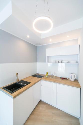 a kitchen with white cabinets and a sink at GRANO APARTMENTS Gdańsk Motława SPA & Wellness in Gdańsk