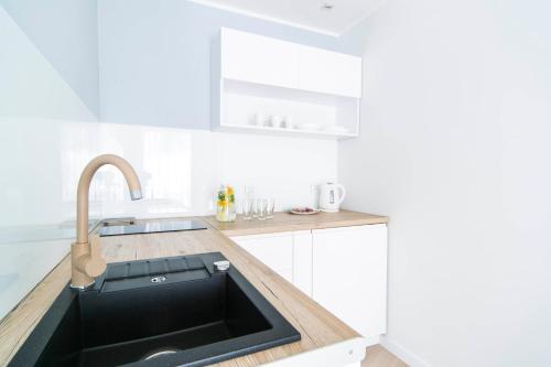 a kitchen with a black sink and a counter at GRANO APARTMENTS Gdańsk Motława SPA & Wellness in Gdańsk