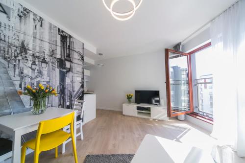 a living room with a table and yellow chairs at GRANO APARTMENTS Gdańsk Motława SPA & Wellness in Gdańsk
