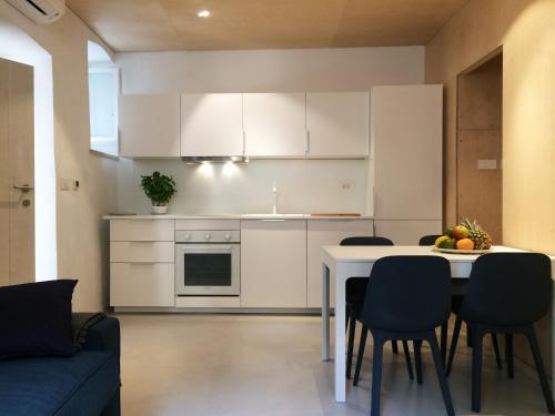uma cozinha com armários brancos e uma mesa e cadeiras em Apartment P 35 em Dubrovnik