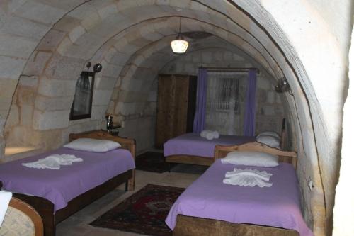 a room with two beds with purple sheets at Relic House in Goreme
