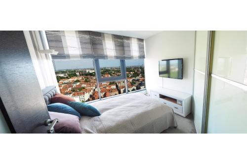 a bedroom with a view of a city from a window at SkyHome in Klaipėda