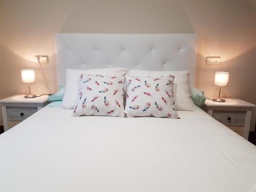 Un dormitorio con una cama blanca con dos lámparas. en Casa Cordieira, en Combarro