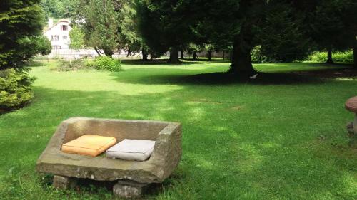 a stone bench sitting in the grass in a yard at Pied des Milles Etang - Les Capucins in Faucogney-et-la-Mer