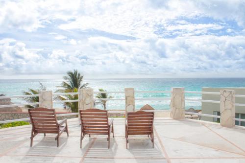 three chairs sitting on a balcony overlooking the ocean at Rodero by Solymar Beach Front Condos in Hotel Zone in Cancún