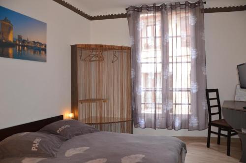 a bedroom with a bed and a desk and windows at La Maison d'Olivier in Beaucaire