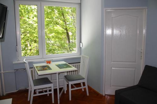 uma pequena mesa e cadeiras num quarto com uma janela em St. Sava Slavija Apartment em Belgrado