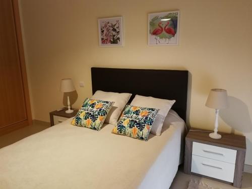 a bedroom with a bed with two pillows and two lamps at Cabanas Apartment in Tavira