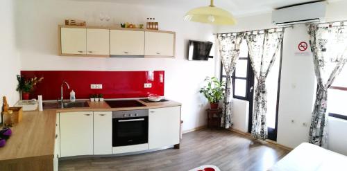 a kitchen with white cabinets and a red wall at Balkaneros Hostel in Mostar