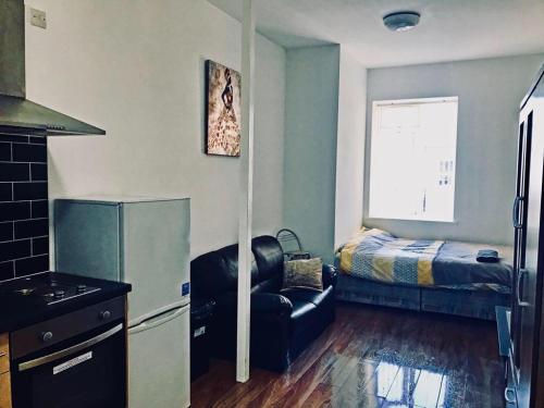 a kitchen with a refrigerator and a chair and a bed at Studio flat in Leicester