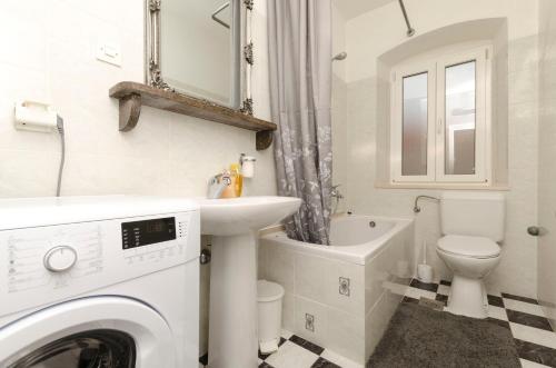 a bathroom with a washing machine and a sink and a toilet at Apartments Jurica in Postira