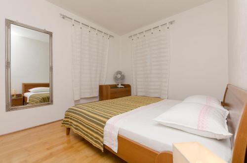 a white bedroom with a bed and a mirror at Apartments Jurica in Postira