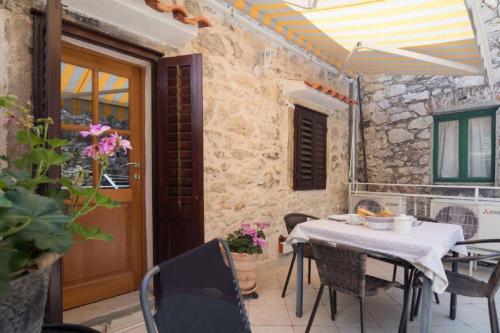een patio met een tafel en stoelen en een deur bij Apartments Lufra Skradin in Skradin