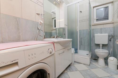 a washing machine in a bathroom with a toilet at Apartments Marinko in Splitska