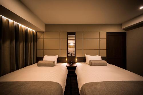 two twin beds in a room with a mirror at The Rise Osaka Kitashinchi in Osaka