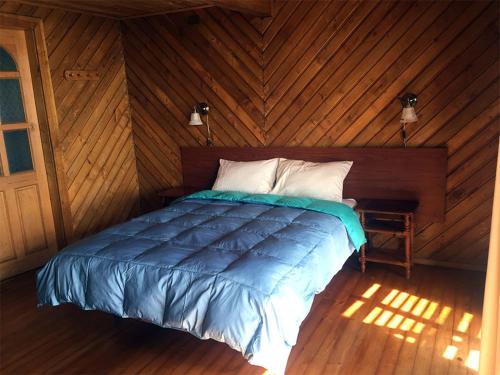 um quarto com uma cama num quarto de madeira em Cabañas Puerto Chalhuaco em Puerto Varas