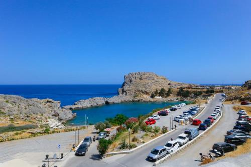 a parking lot with cars parked next to the ocean at St. Paul's Bay View Suites in Líndos