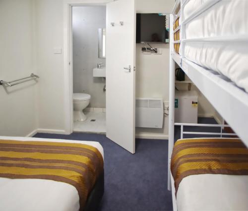 アダミナビーにあるSelwyn Star Lodgeの二段ベッド2台、バスルームが備わる小さな客室です。