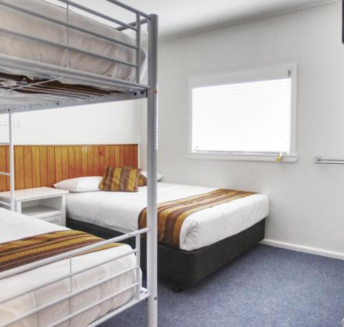 a bedroom with two bunk beds and a window at Selwyn Star Motel in Adaminaby