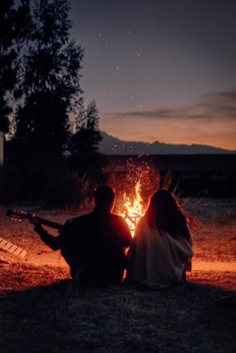 a couple sitting in front of a fire at night at Casona Plaza Ecolodge Colca in Yanque