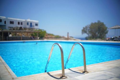 a swimming pool with blue water and metal rails at Two level house on the Beach in Agios Ioannis Mykonos