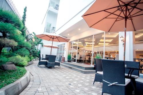 a patio with tables and chairs and an umbrella at Savero Hotel Depok in Depok