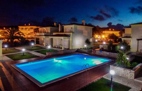 a swimming pool in front of a house at night at Praia Del Rei Pool View in Casal da Lagoa Seca