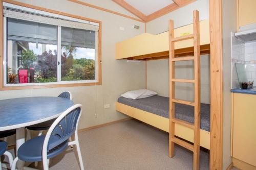 a small room with a bunk bed and a table and chair at BIG4 Park Beach Holiday Park in Coffs Harbour