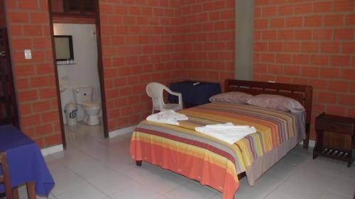 a bedroom with a bed and a brick wall at Hotel Ambaibo in Rurrenabaque
