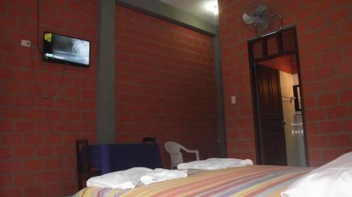 a bedroom with a bed and a tv on a brick wall at Hotel Ambaibo in Rurrenabaque