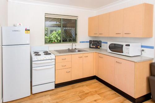 a kitchen with a white refrigerator and a microwave at BIG4 Park Beach Holiday Park in Coffs Harbour
