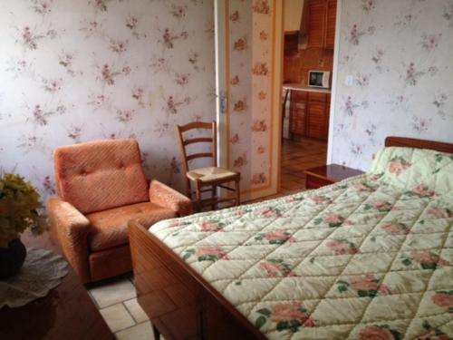 - une chambre avec un lit et une chaise dans l'établissement Gîte des Géraniums, à Crestet