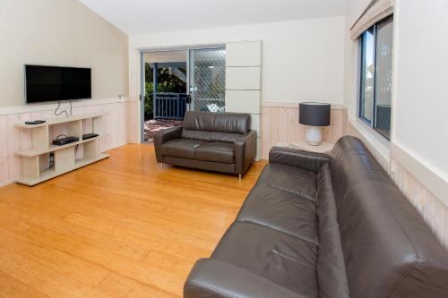 a living room with a leather couch and a television at BIG4 Park Beach Holiday Park in Coffs Harbour