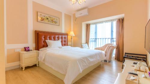 a bedroom with a large white bed and a window at Guangzhou Laiste ApartHotel（Pazhou Exhibition Center Branch） in Guangzhou