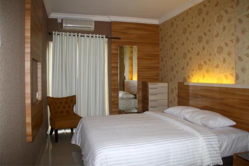 マナドにあるMTC Mega Mas Apartmentのベッドルーム(白いベッド1台、椅子付)