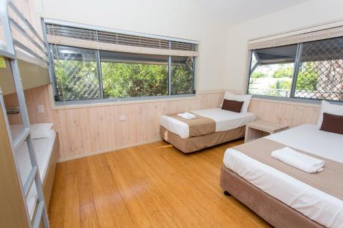 a room with two beds and a couch and two windows at BIG4 Park Beach Holiday Park in Coffs Harbour