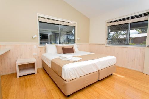a bedroom with a large bed and two windows at BIG4 Park Beach Holiday Park in Coffs Harbour